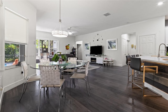 dining room featuring a ceiling fan, dark wood-style flooring, visible vents, crown molding, and baseboards