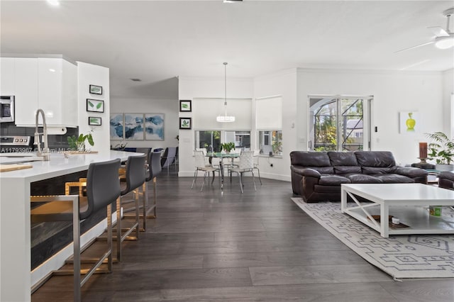 living area with a ceiling fan, baseboards, and dark wood finished floors