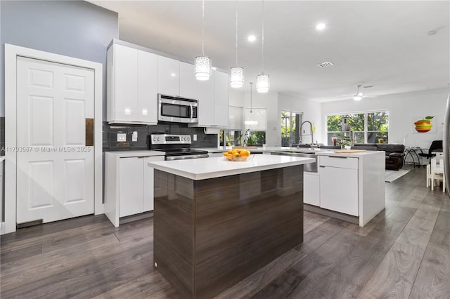 kitchen featuring dark wood-type flooring, a peninsula, modern cabinets, and stainless steel appliances