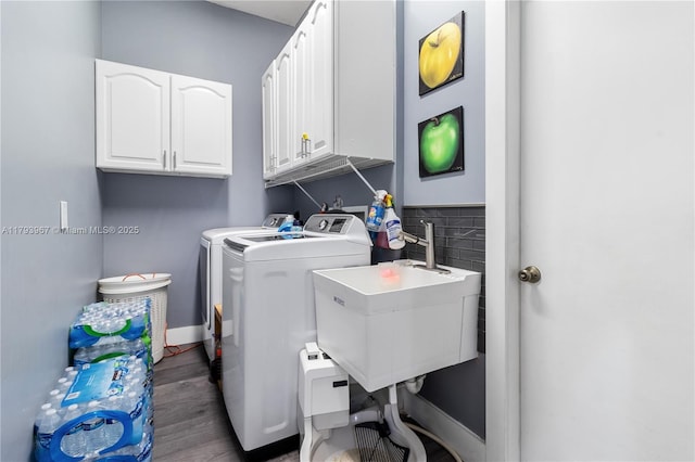 clothes washing area featuring wood finished floors, baseboards, washer and clothes dryer, a sink, and cabinet space