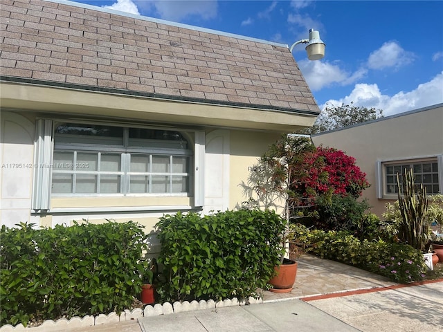 details featuring roof with shingles and stucco siding