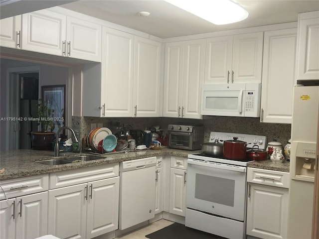 kitchen with white appliances, white cabinets, and a sink