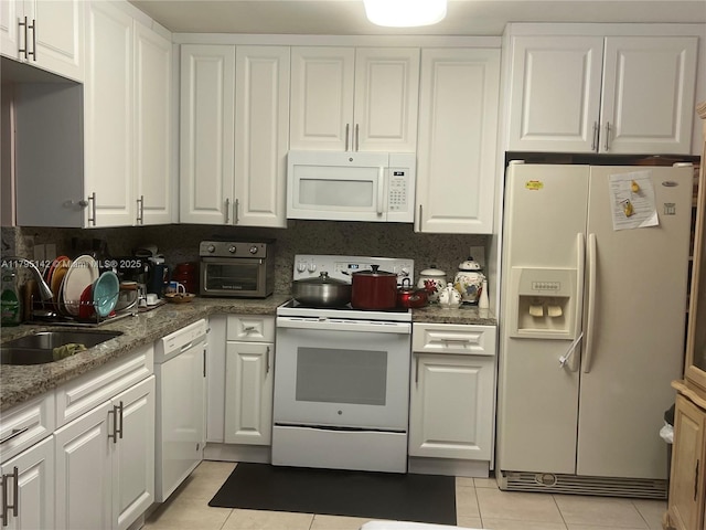 kitchen featuring white appliances, light tile patterned flooring, white cabinets, and a sink