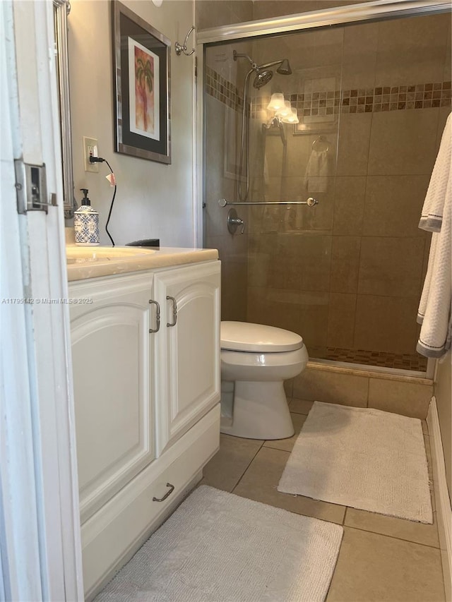 bathroom with tile patterned flooring, a stall shower, toilet, and vanity