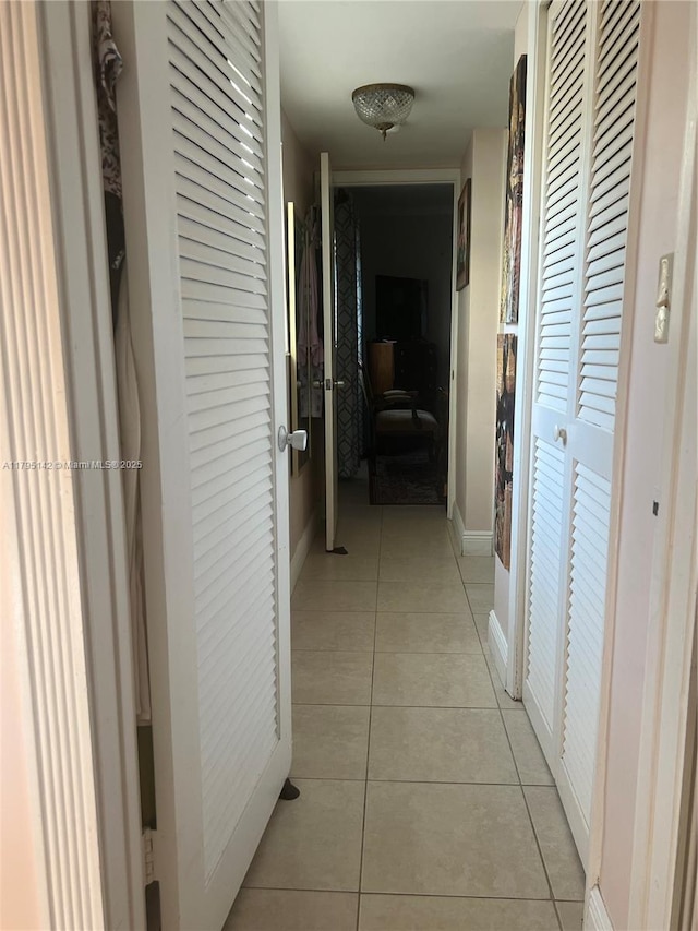 corridor featuring light tile patterned flooring, baseboards, and french doors