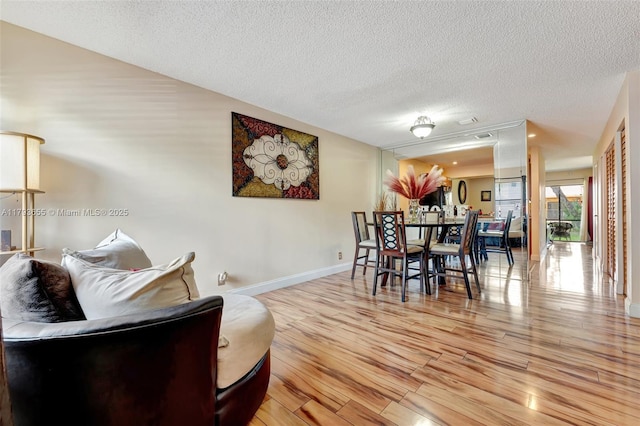 dining area with baseboards, a textured ceiling, and light wood finished floors