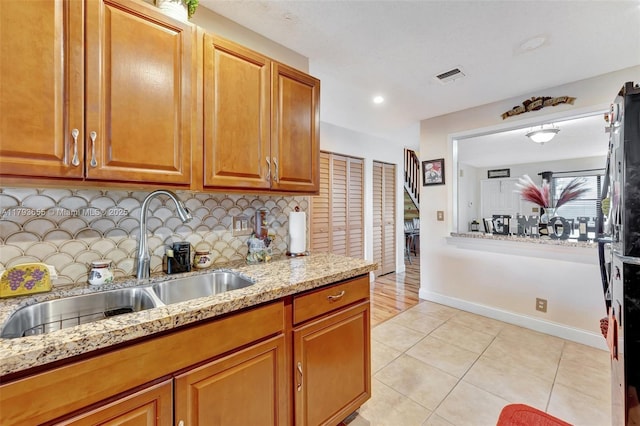 kitchen featuring visible vents, decorative backsplash, light tile patterned flooring, light stone counters, and a sink