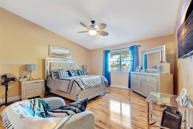 bedroom featuring baseboards, light wood-style flooring, ceiling fan, and lofted ceiling
