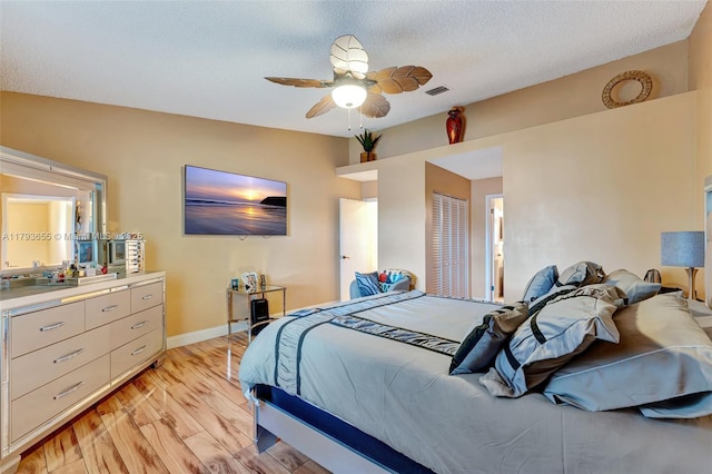 bedroom with light wood-style flooring, a ceiling fan, baseboards, visible vents, and a closet