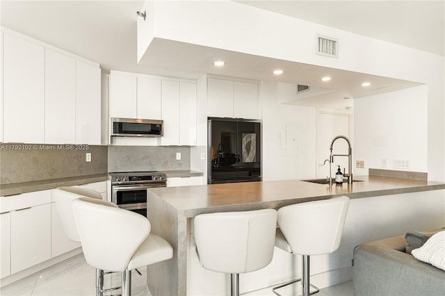 16485 Collins Ave Unit 2438, Sunny Isles Beach, FL 33160 - kitchen with appliances with stainless steel finishes, a sink, a peninsula, decorative backsplash, and a kitchen bar