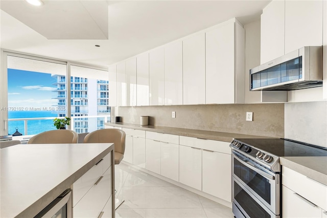 16485 Collins Ave Unit 2438, Sunny Isles Beach, FL 33160 - kitchen with white cabinetry, appliances with stainless steel finishes, decorative backsplash, and wine cooler