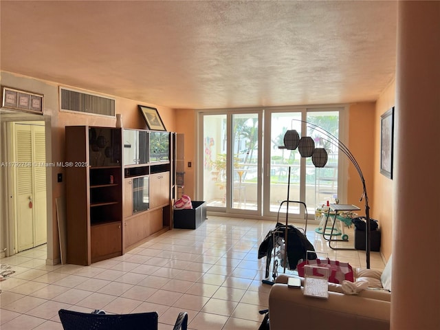 5005 Collins Ave Unit 214, Miami Beach, FL 33140 - living area featuring visible vents, a textured ceiling, light tile patterned flooring, and a wall of windows