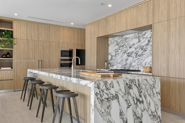 310 W Dilido Dr, Miami Beach, FL 33139 - kitchen with appliances with stainless steel finishes, modern cabinets, light stone countertops, a kitchen bar, and recessed lighting