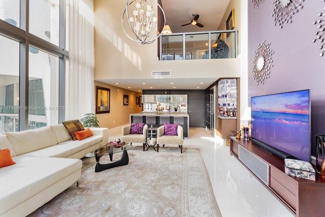living room with visible vents, ceiling fan with notable chandelier, and a high ceiling