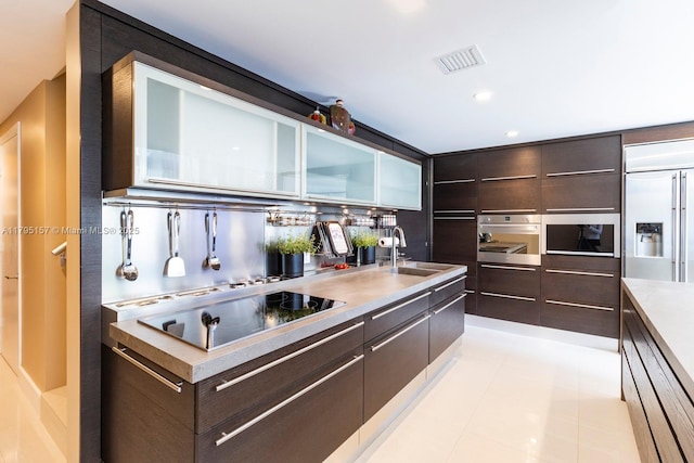 kitchen featuring a sink, appliances with stainless steel finishes, modern cabinets, and dark brown cabinetry
