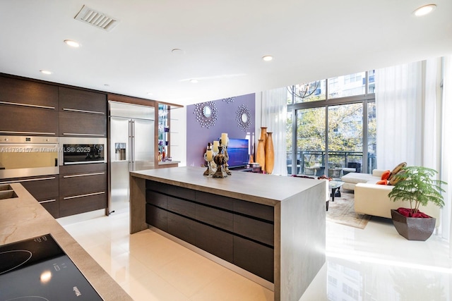 kitchen featuring dark brown cabinetry, appliances with stainless steel finishes, light countertops, visible vents, and modern cabinets