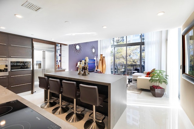 kitchen featuring dark brown cabinetry, a kitchen island, a kitchen bar, visible vents, and modern cabinets