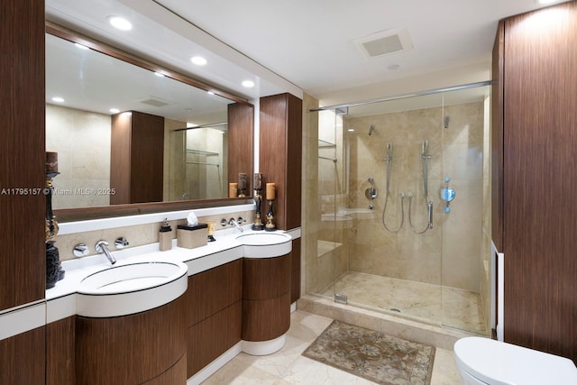 full bath featuring visible vents, double vanity, toilet, a shower stall, and a sink