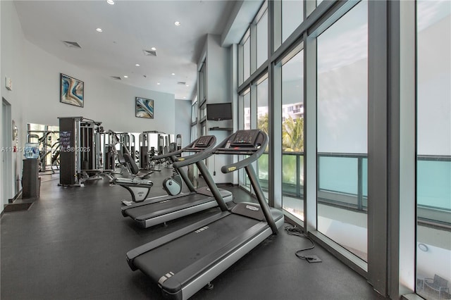 exercise room featuring a towering ceiling, recessed lighting, and visible vents