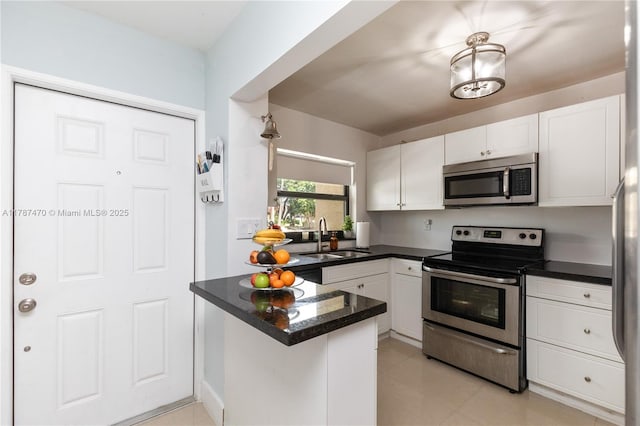 8956 Palm Tree Ln Unit 8956, Pembroke Pines, FL 33024 - kitchen featuring appliances with stainless steel finishes, dark countertops, a sink, white cabinets, and a peninsula
