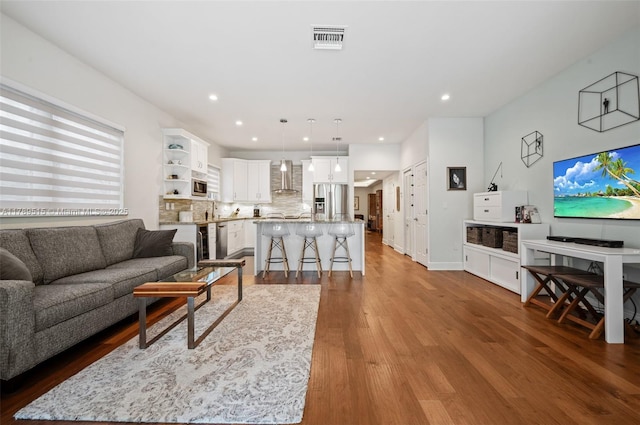 living room featuring baseboards, recessed lighting, wood finished floors, and visible vents