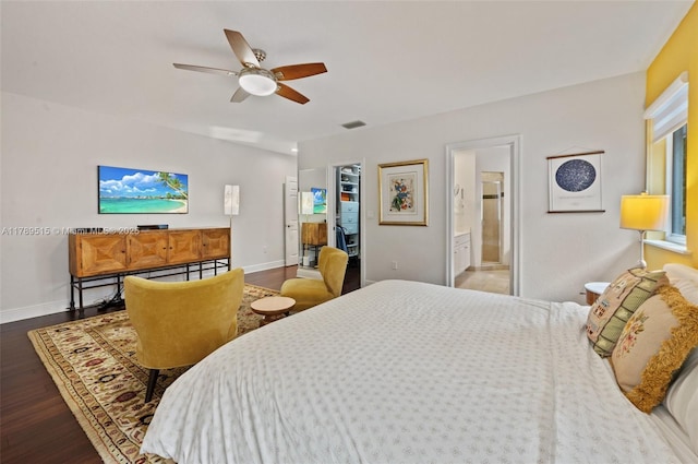 bedroom with connected bathroom, a ceiling fan, baseboards, wood finished floors, and visible vents
