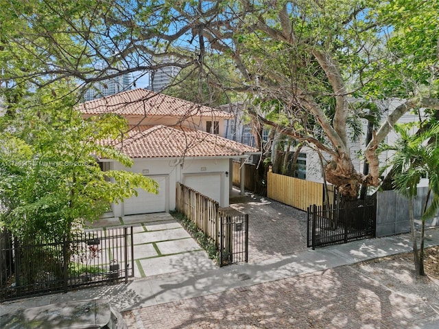 view of front of home with stucco siding, a gate, a fenced front yard, driveway, and a tile roof