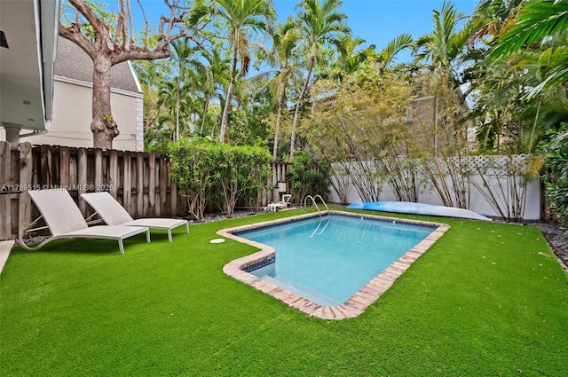 view of swimming pool with a lawn, a fenced in pool, and a fenced backyard