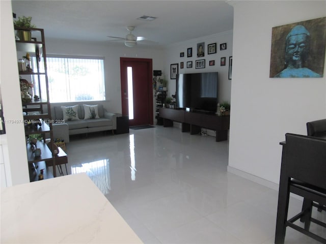 living room with visible vents, a ceiling fan, baseboards, and crown molding