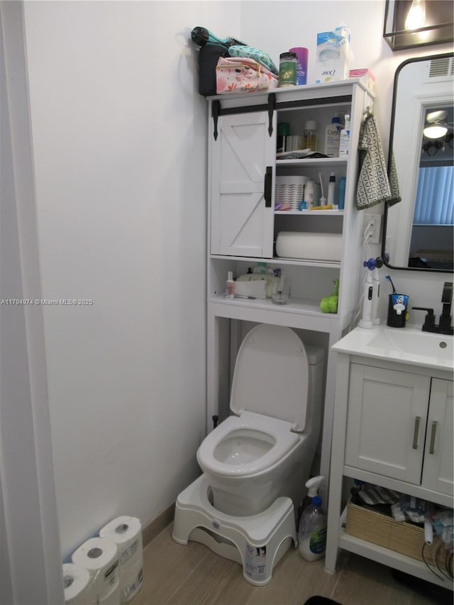 bathroom with vanity, toilet, and wood finished floors