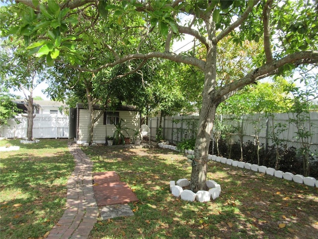 view of yard with an outdoor structure, a fenced backyard, and a shed