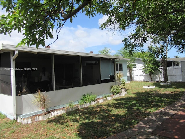 rear view of property featuring fence, a yard, and a sunroom