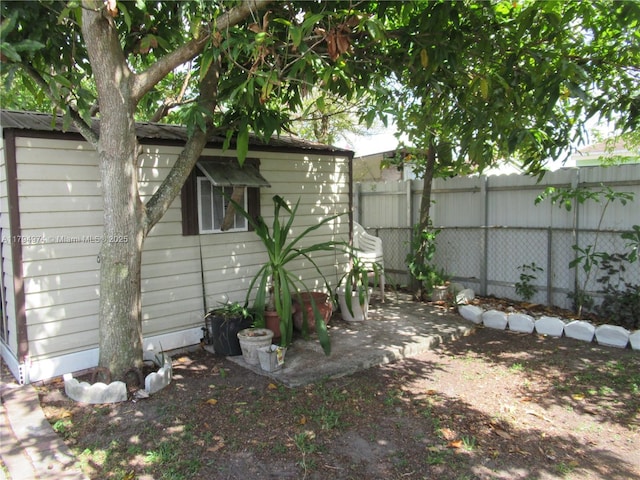 view of yard featuring a patio, fence, and an outbuilding