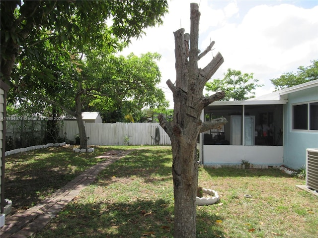 view of yard with a fenced backyard, central AC unit, and a sunroom