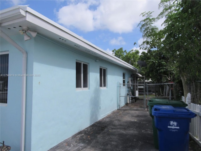 view of side of property featuring fence and stucco siding