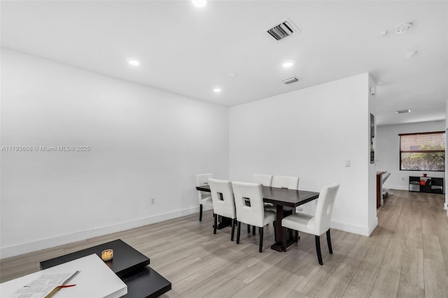 dining space with light wood finished floors, baseboards, and visible vents