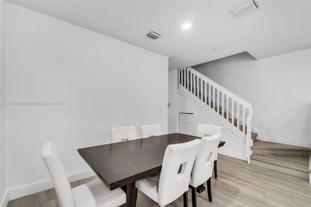 dining room with stairway, light wood finished floors, baseboards, and visible vents