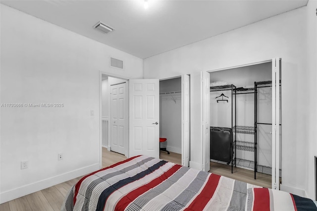 bedroom with baseboards, visible vents, and wood finished floors