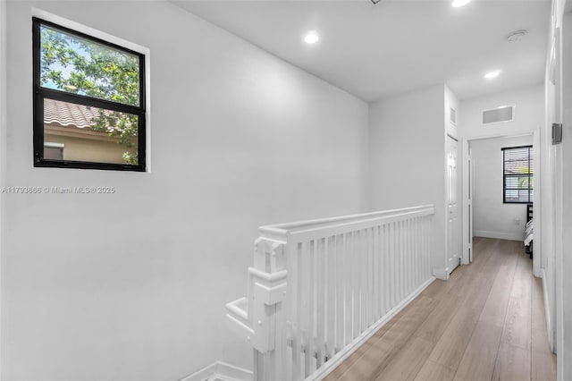 hall featuring light wood-style floors, visible vents, an upstairs landing, and recessed lighting