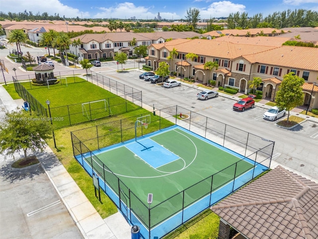 view of basketball court featuring a yard, fence, community basketball court, and a residential view