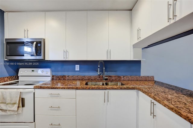 kitchen with a sink, white cabinets, stainless steel microwave, dark stone counters, and white electric range oven