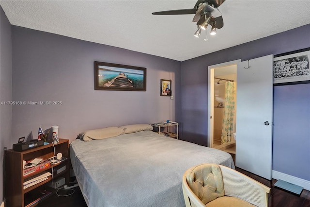 bedroom featuring connected bathroom, baseboards, ceiling fan, and wood finished floors