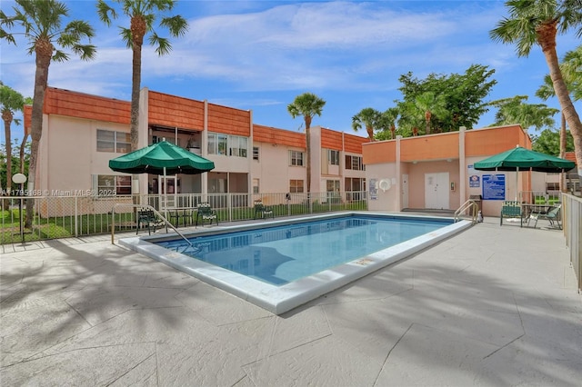 community pool with fence and a patio
