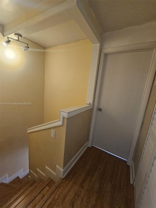 stairway with baseboards, wood finished floors, and beam ceiling
