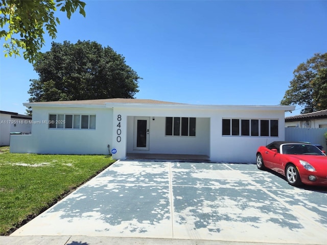 ranch-style house with fence, a front yard, and stucco siding