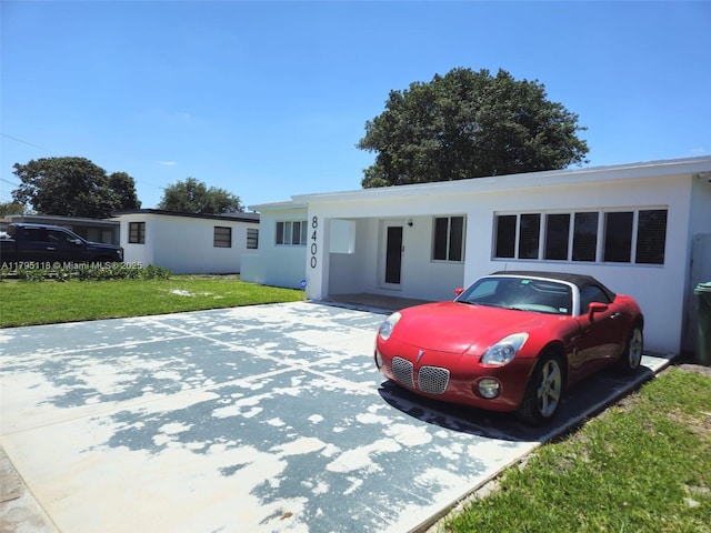ranch-style home featuring stucco siding and a front lawn