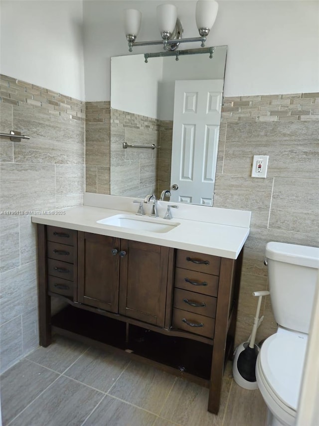 half bath with tile walls, vanity, and toilet