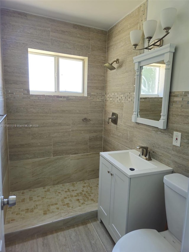 full bath featuring vanity, wood finished floors, toilet, tile walls, and tiled shower