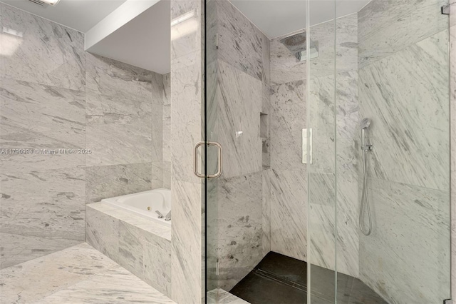 bathroom with a marble finish shower, a bath, and tile walls