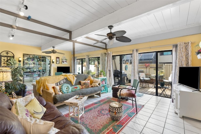 living area featuring plenty of natural light, a ceiling fan, rail lighting, beam ceiling, and light tile patterned flooring